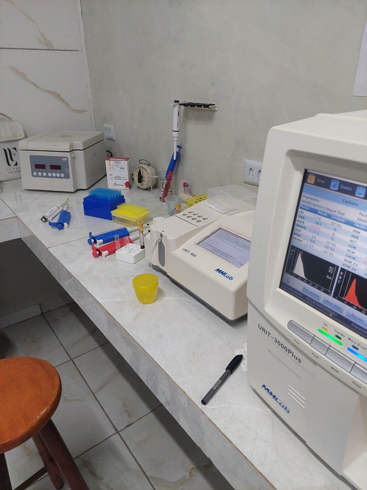 Bancada do laboratório interno com centrífuga, pipetas e analisador bioquímico